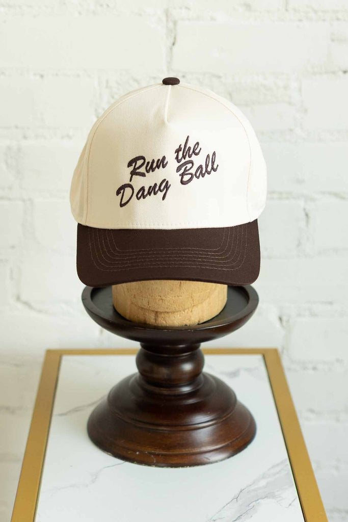 run the dang ball hat, funny football cap, game day trucker hat, embroidered snapback, brown and cream hat, sporty boutique cap, adjustable sports cap, bold fan statement hat, two-tone game day accessories, football season merch