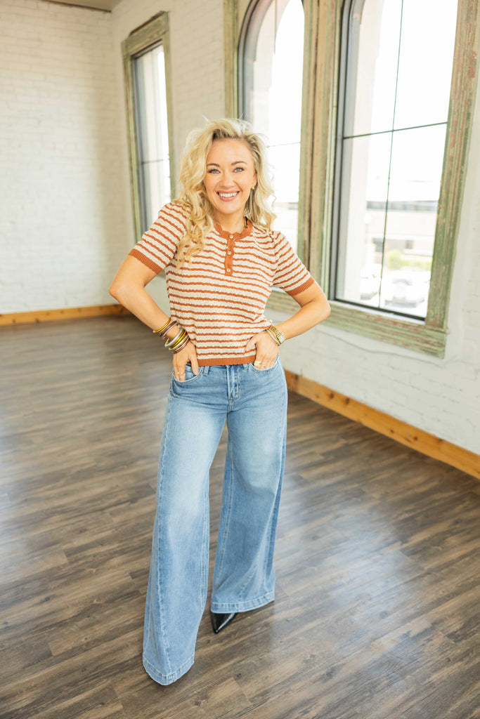 Woman wearing cropped striped knit top in cinnamon and ivory with short sleeves and button front.