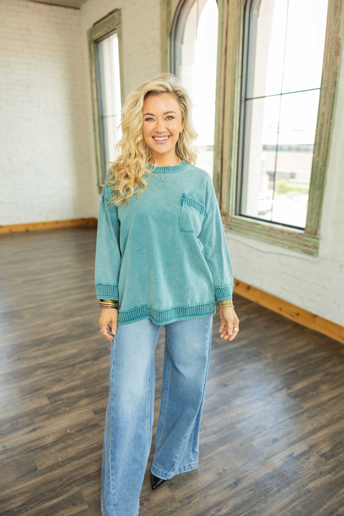 Woman wearing teal mineral wash oversized pullover top with 3/4 wide sleeves and crochet trim.