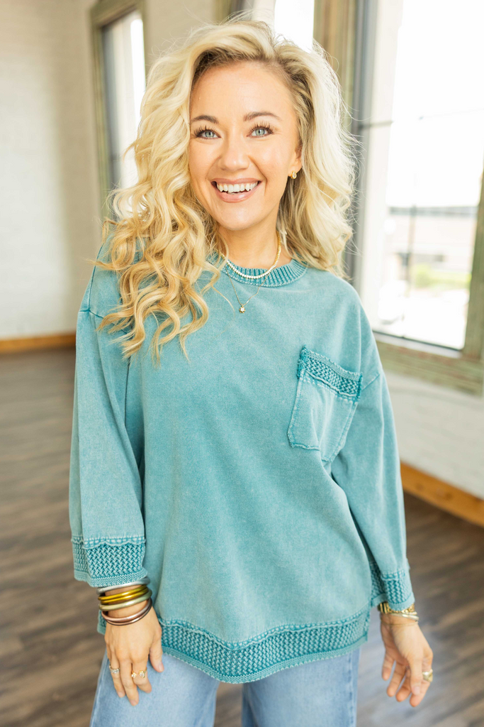 Woman wearing teal mineral wash oversized pullover top with 3/4 wide sleeves and crochet trim.