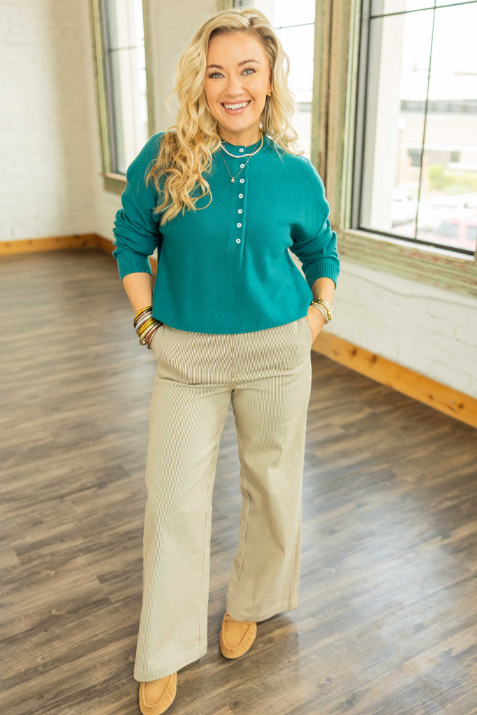 Woman wearing teal lightweight henley quarter button up sweater top with long sleeves.