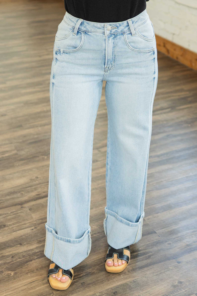 Light wash wide leg jeans with high rise waist, cuffed hem, and seam detail, styled with casual tops.