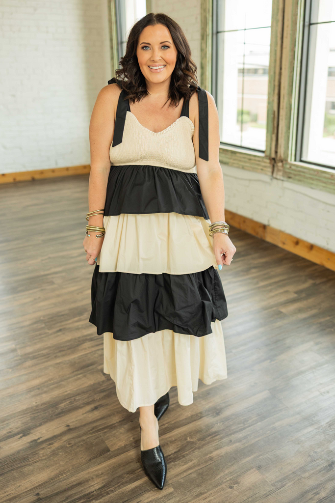 Plus size model wearing a black and cream tiered maxi dress with smocked bodice and tie straps.