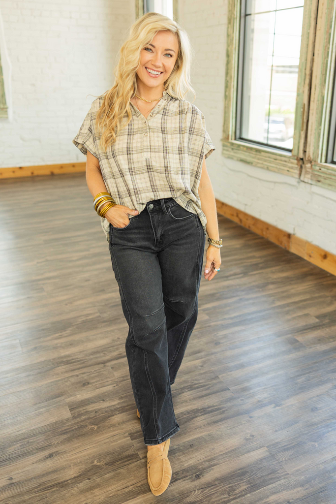 Woman wearing a beige plaid quarter button blouse with green and black stripes, relaxed fit, and high-low hem.