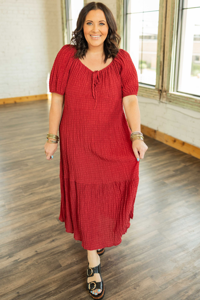 brunette plus sized woman wearing a red smocked boho midi dress with puff sleeves and tiered skirt.