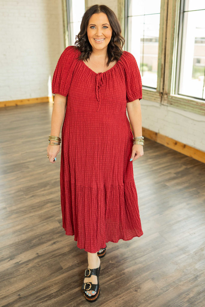brunette plus sized woman wearing a red smocked boho midi dress with puff sleeves and tiered skirt.