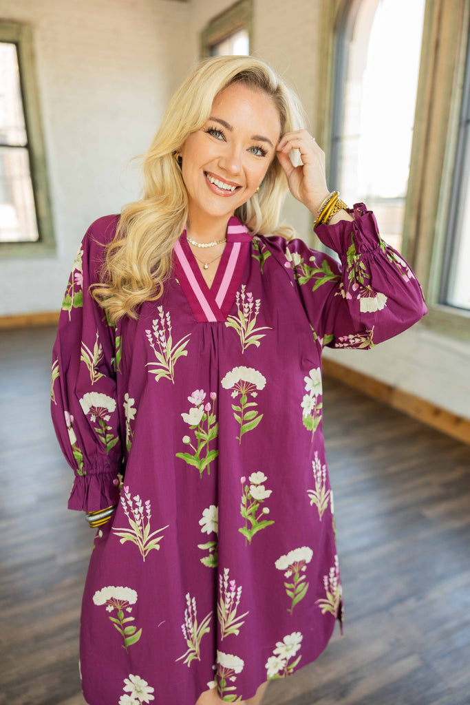 Holly wearing a plum floral tunic mini dress with 3/4 ruffle sleeves, contrast V-neckline, and side pockets