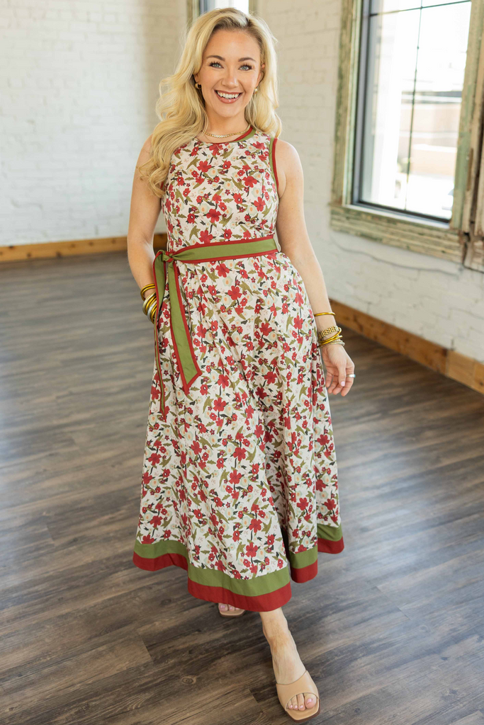 Holly wearing a sleeveless fall floral midi dress with red and olive tones, multicolor trim, and a removable belt.