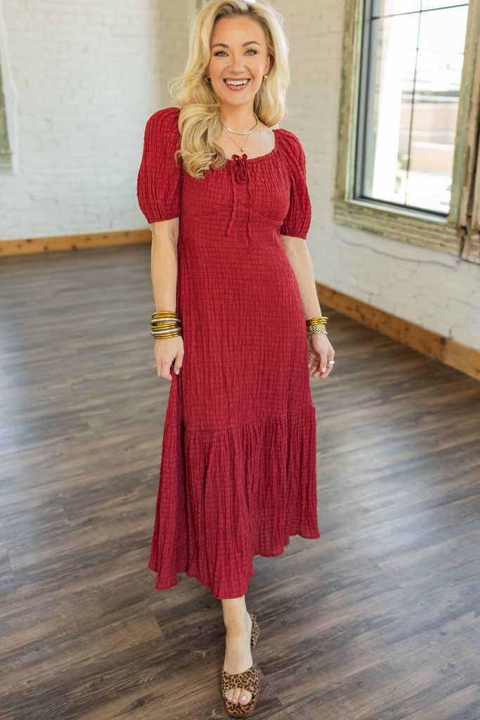 Blonde woman wearing a red smocked boho midi dress with puff sleeves and tiered skirt.
