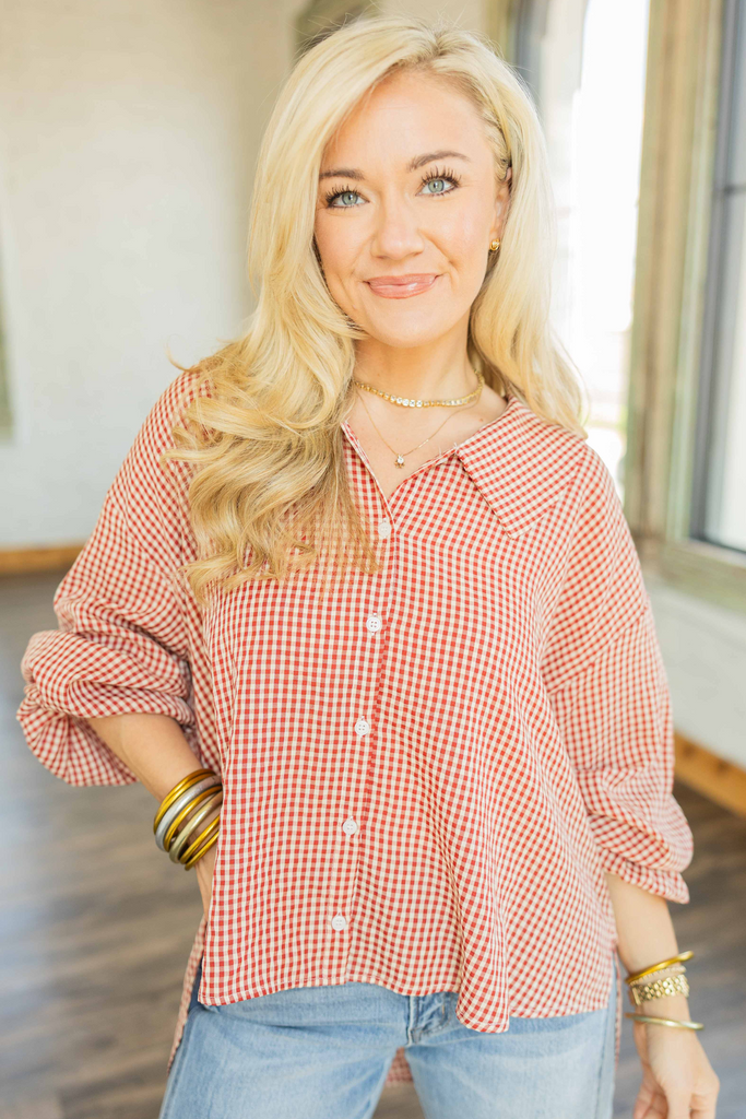 Woman wearing oversized red and ivory gingham button-down top with sailor collar and balloon sleeves styled with light wash denim BARREL jeans.