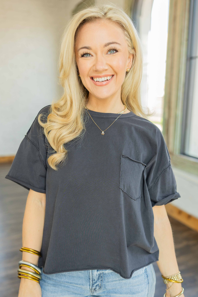 Woman wearing charcoal gray raw edge relaxed crop knit cotton top styled with light wash denim jeans.