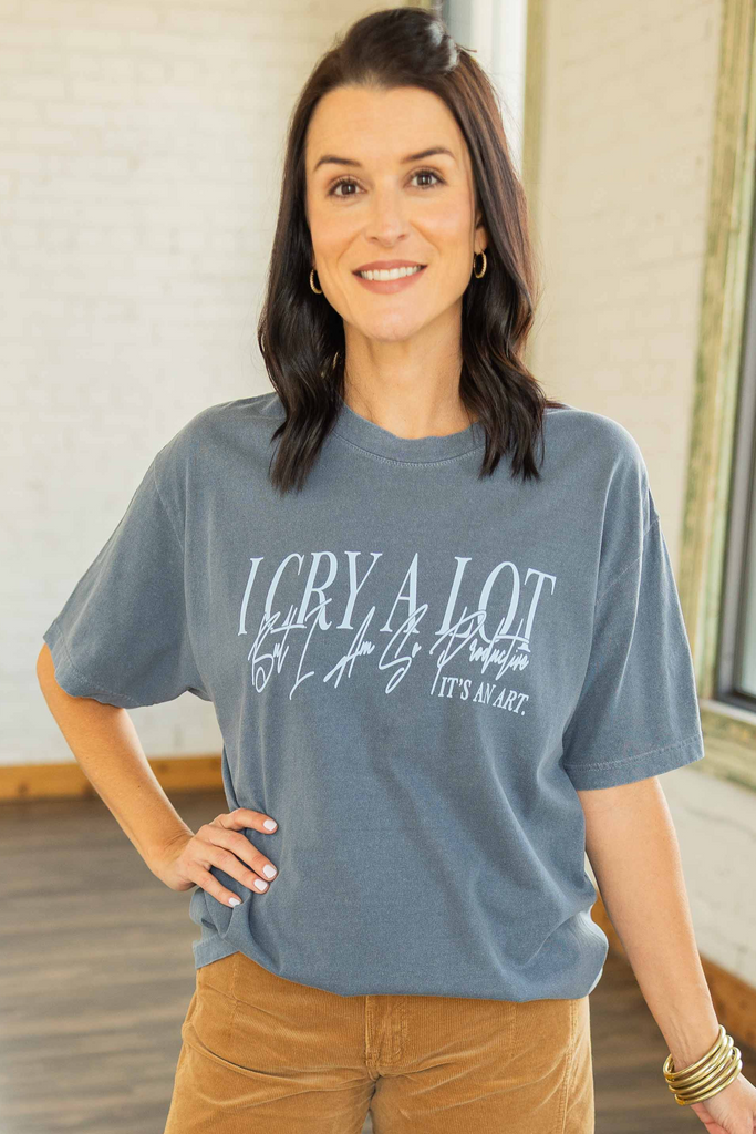 wearing a blue oversized graphic tee that says “I Cry A Lot, It’s An Art” paired with camel corduroy pants and sneakers.