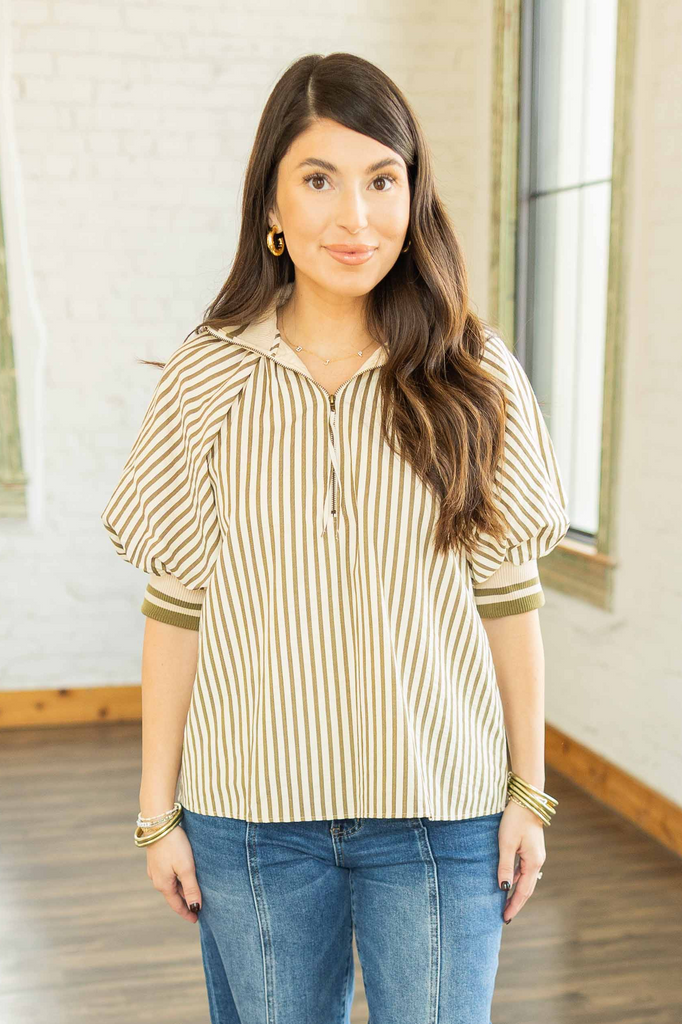 Kayla wearing a cream and olive green striped quarter zip pullover top with contrast collar and elastic hem, paired with denim jeans.