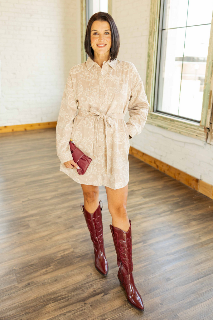 Kandace wearing the Emory taupe embroidered button-up mini dress with paisley design, self-tie belt, and burgundy boots