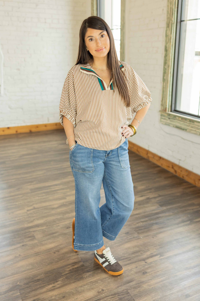 Kayla wearing the Jordan cinnamon and cream striped dolman top with teal neckline trim and light wash jeans