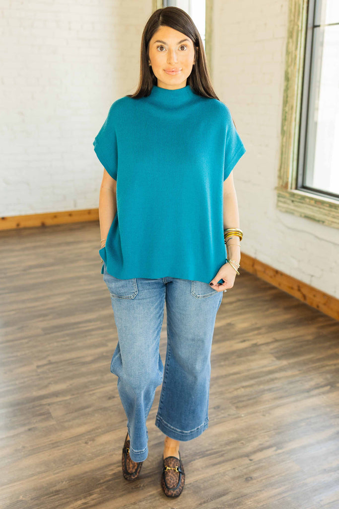 Kayla wearing the Virginia teal mock neck cap sleeve sweater top with light wash jeans