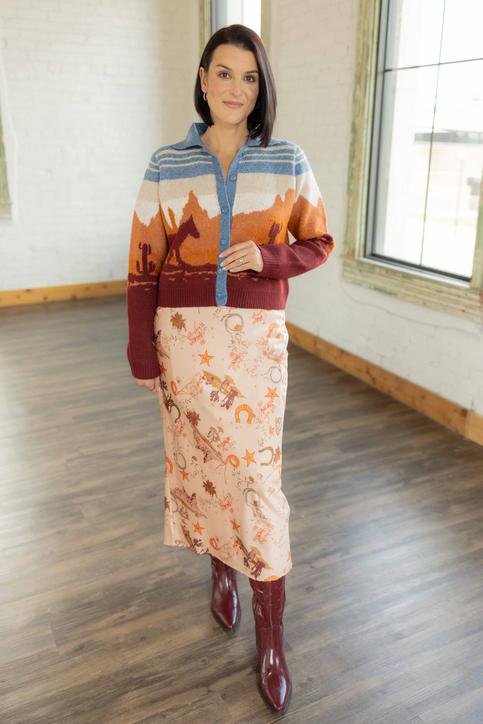 Kandace wearing the Zuri cream western print slip midi skirt with orange and brown cowboy-inspired pattern and rust sweater top