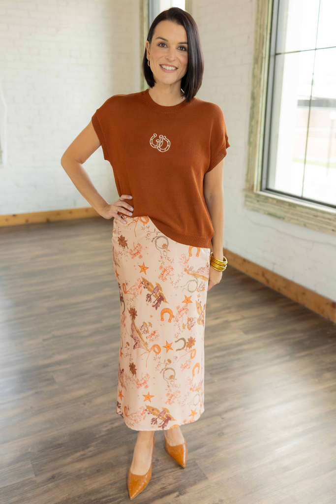 Kandace wearing the Drew rust knit cap sleeve top with embroidered horseshoe detail paired with a western print slip skirt