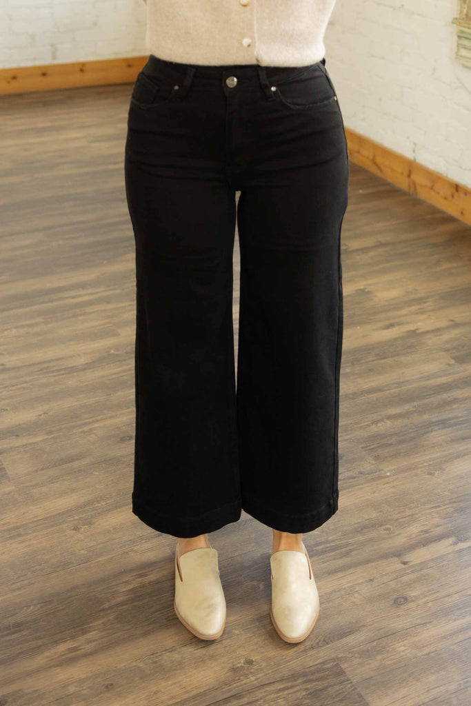 Kayla wearing the Risen Maria high rise ankle wide leg jeans in solid black denim with beige sweater and ivory loafers
