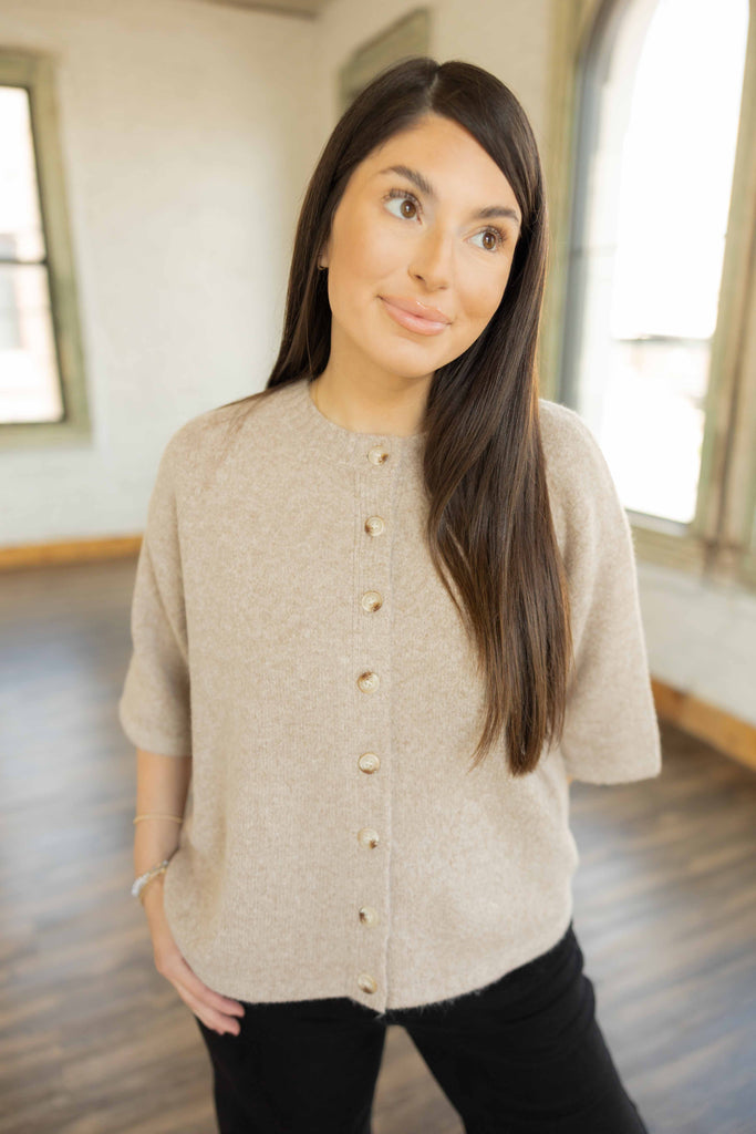 Kayla wearing the Hallie 3/4 sleeve button up sweater top in soft oatmeal color with gold buttons, styled with black pants