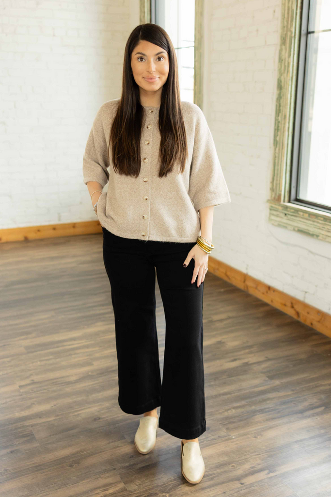 Kayla wearing the Hallie 3/4 sleeve button up sweater top in soft oatmeal color with gold buttons, styled with black pants