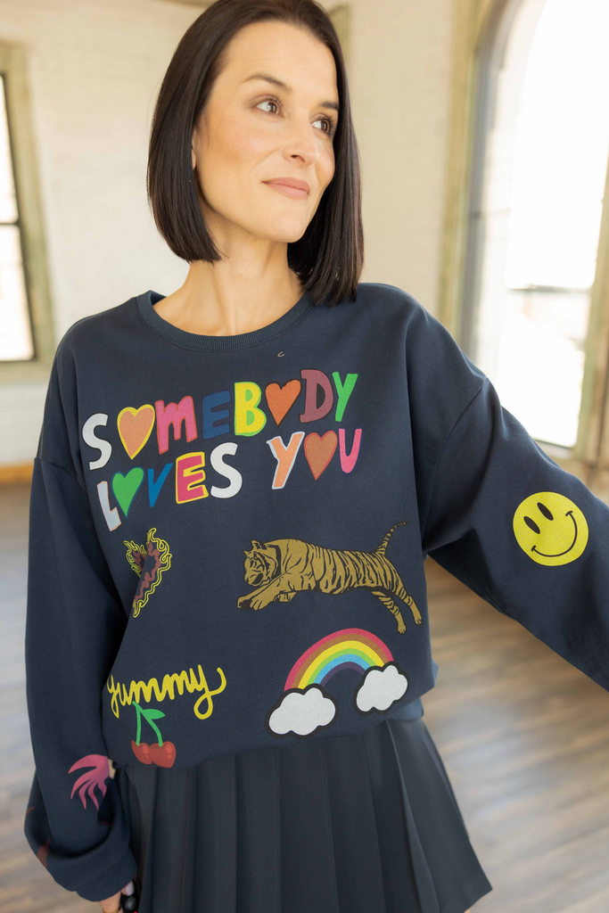 Kandace wearing the Somebody Loves You navy crewneck with colorful hand-drawn graphics and a pleated NAVY skort