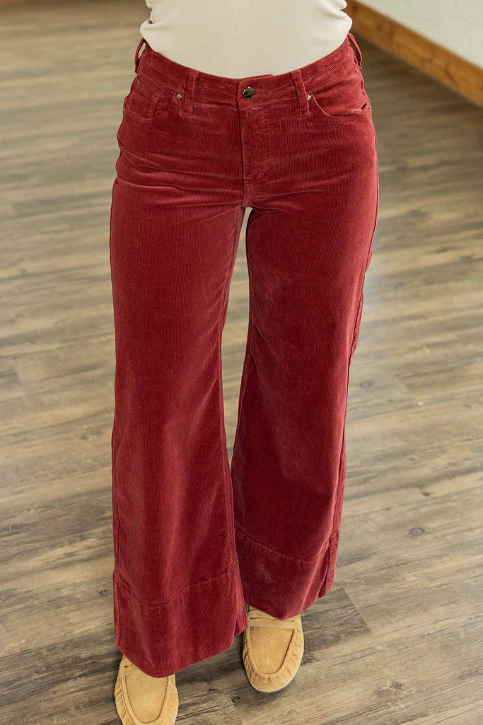 Holly wearing the [RISEN] Winnie High Rise Cropped Corduroy Jeans, wine-maroon cropped wide-leg corduroy pants with a trouser hem, styled with a light gray ringer tee and white sneakers.